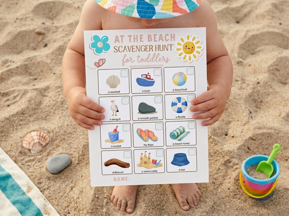 A Toddler holds the Beach Scavenger Hunt page, standing on the sand wearing a sunhat.