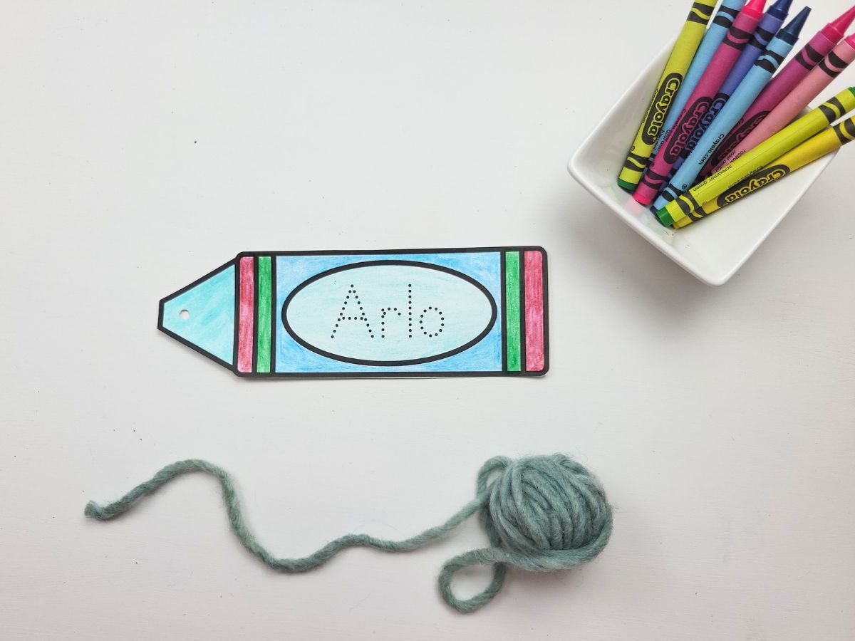 A Crayon Bookmark printout with some crayons and yarn beside.