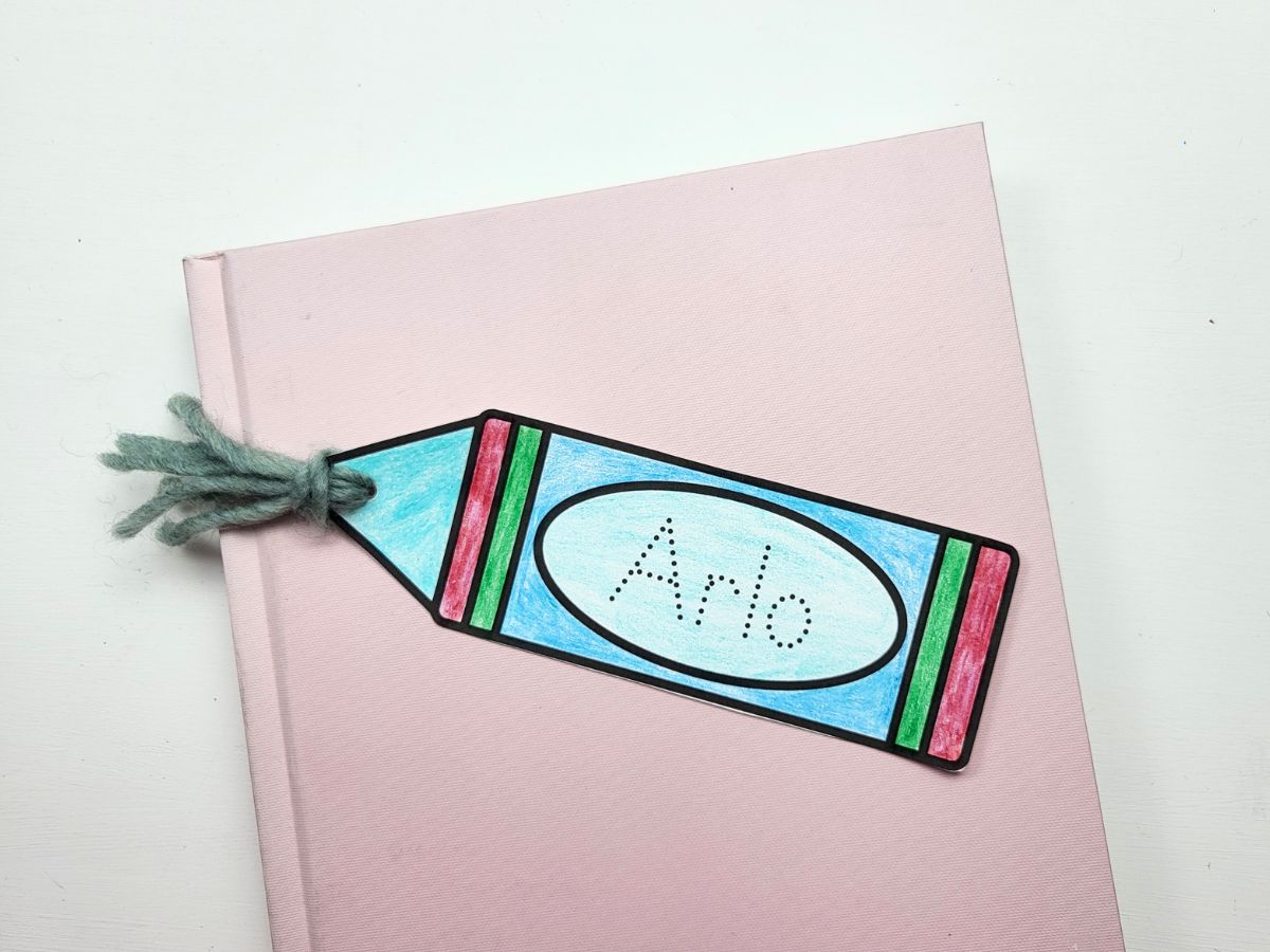 Completed crayon name bookmark lying on a pink book. 