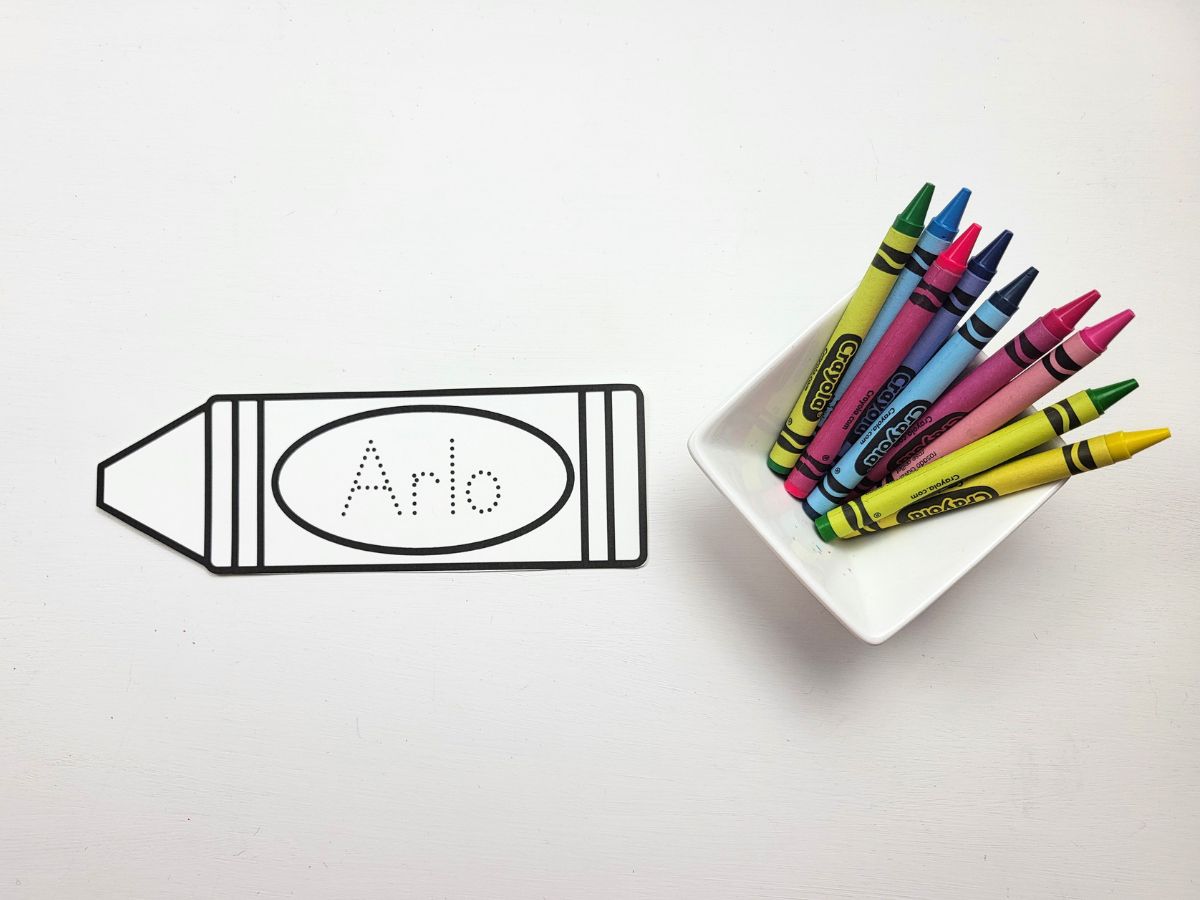 A crayon name bookmark beside a small dish of crayons. 